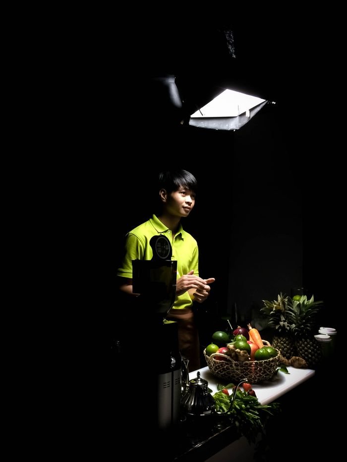 Man preparing fresh fruit in a dimly lit kitchen, showcasing a modern culinary workspace.