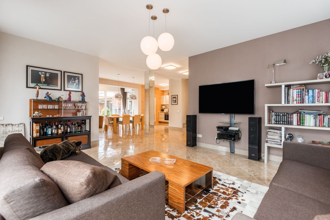 Interior of spacious living room with comfortable sofa near wooden table and TV with bookshelves