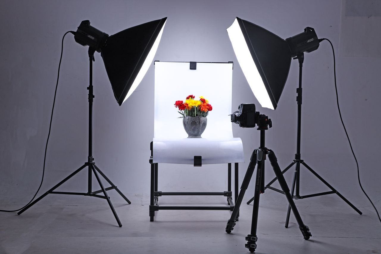 Studio setup with lights and camera capturing flowers in a vase, ideal for product photography.